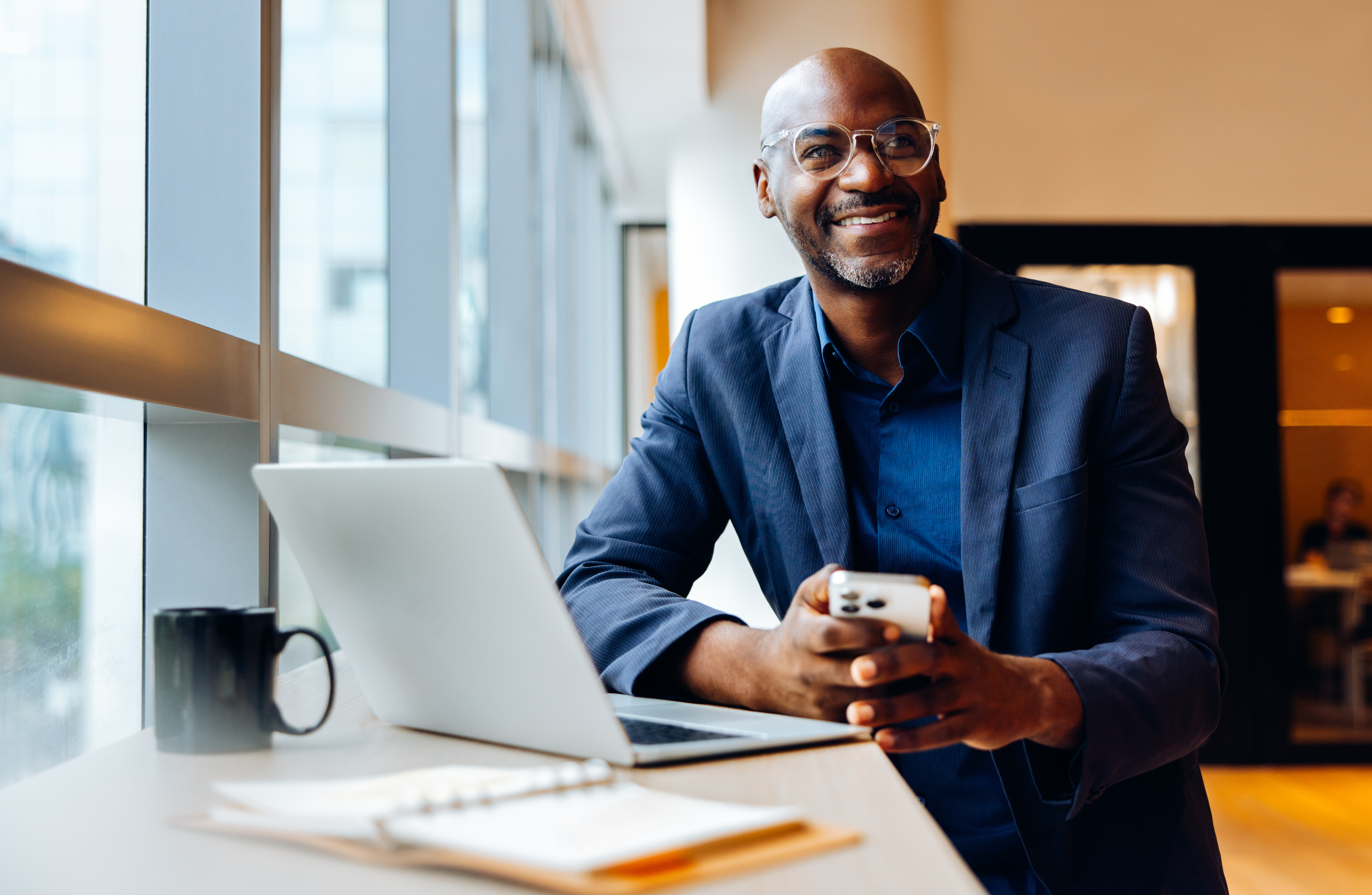 Un homme souriant consulte son téléphone à son bureau.